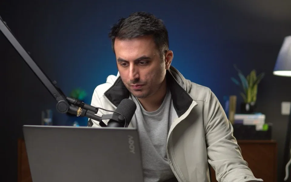 Moiz Khan at his desk with a podcast microphone and laptop